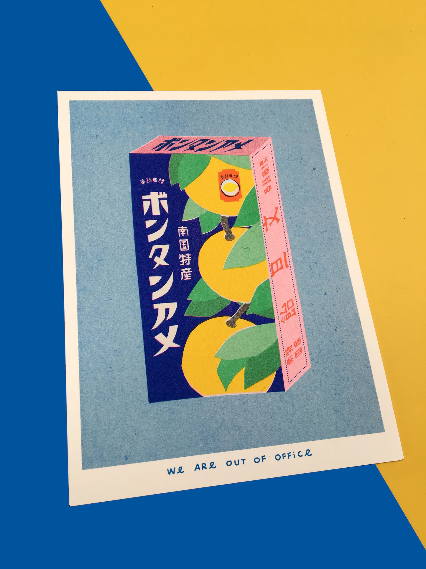 Japanese Candy Box risograph print by We Are Out of Office – vibrant pop-art style illustration of a vintage Japanese bonbon box with yellow fruit and kanji, printed with soy ink on 300g Biotop paper in the Netherlands.