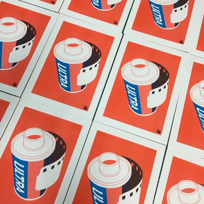 "Film Roll" by VrijFormaat – bold minimalist illustration of a retro 35mm film canister labeled “Ultra” in red, white, and blue, evoking vintage photography nostalgia and modern pop art aesthetics; a perfect gift for analog film lovers and creative wall decor, available at Galerie Frits