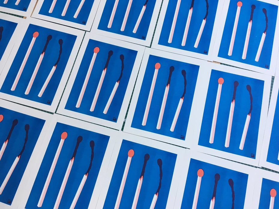 Minimalist risograph art print of three red and blue matchsticks in various stages of burning, designed by VrijFormaat on A4 Biotop paper.