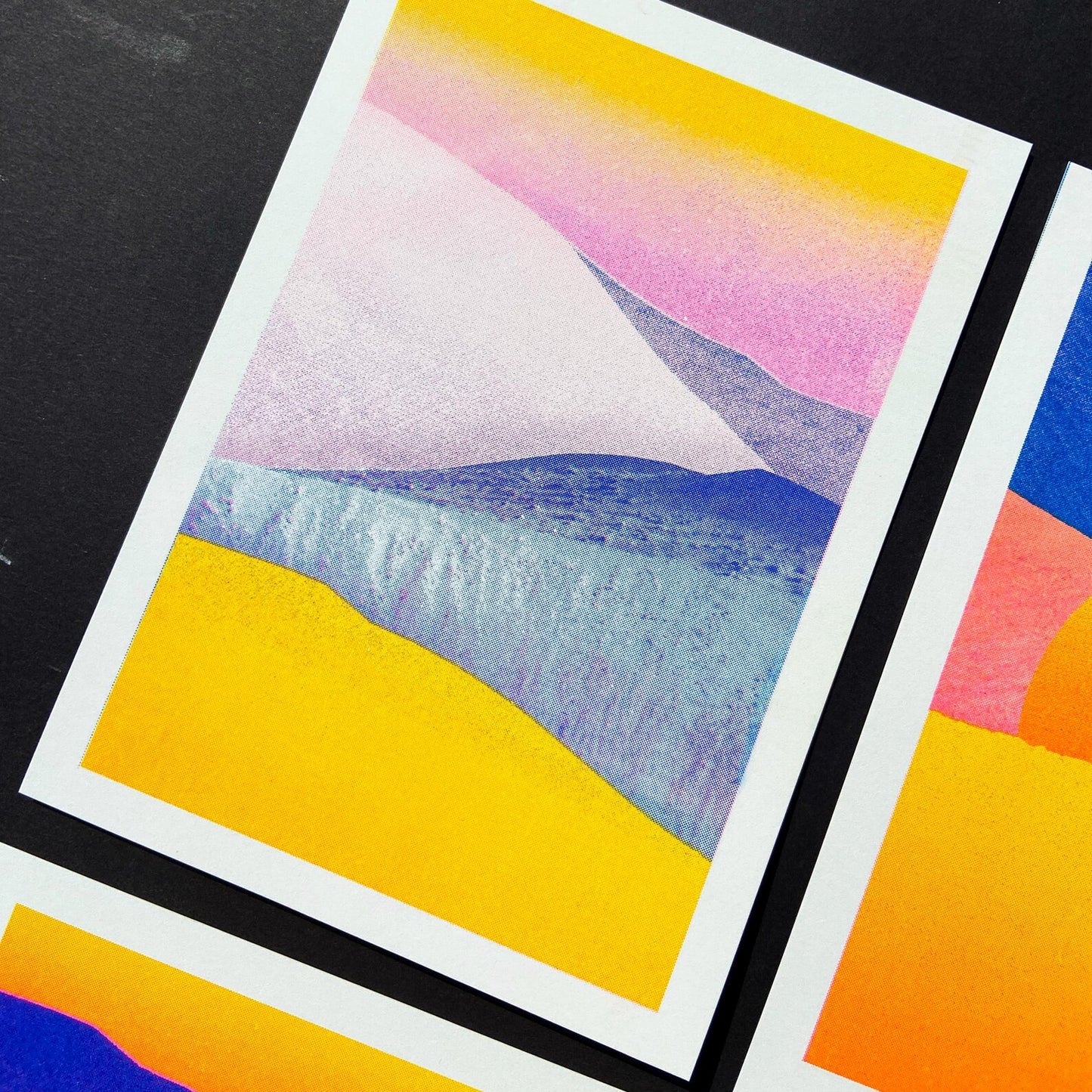 Minimal pastel landscape risograph print by Dutch illustrator PTRVRKD featuring yellow sand dunes, blue hills, and a soft pink sky gradient. Handmade 12.5 x 17.5 cm art print on Biotop 250 gsm paper with soy-based inks. Ideal wall art for modern interiors, Scandinavian style, or desert-inspired home décor.