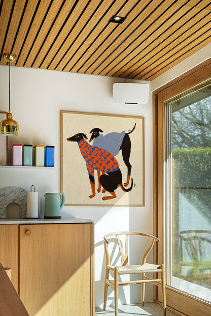 Colorful Doggos art print by Enikő Eged featuring two stylized black dogs wearing patterned sweaters in blue, orange, and grey tones on a warm neutral background, square contemporary giclée wall art for modern interiors.