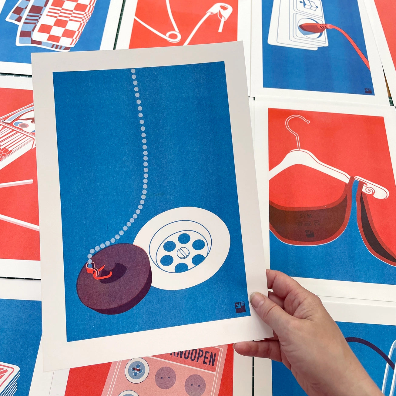 Minimalist risograph art print of a kitchen sink drain and plug, designed in vivid red and blue by Dutch studio VrijFormaat. Modern pop-art style illustration from the “Extra Ordinary” series, celebrating everyday household objects. Printed on Biotop paper, A4 size, made in Utrecht, the Netherlands.