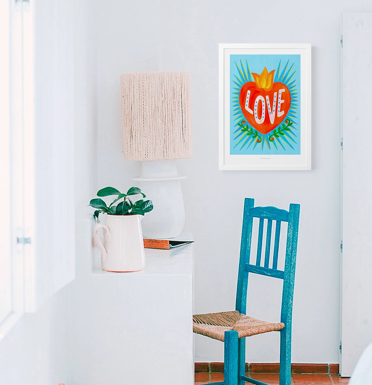 Bright Mexican folk-style illustration of a red heart with yellow flames and the word “LOVE” in white letters on a turquoise blue background, surrounded by green leaves – vibrant Giclée art print by Just Cool Design.