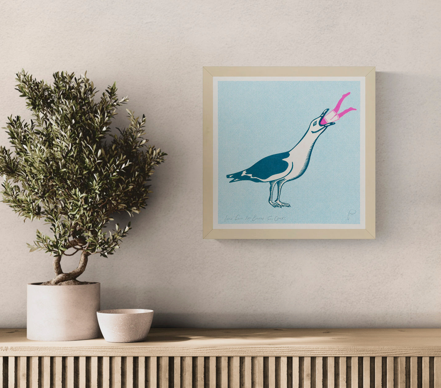 Square risograph print by Strangford showing an oversized teal and cream seagull swallowing a tiny pink swimmer against a pale blue dotted background, playful contemporary wall art for eclectic interiors.