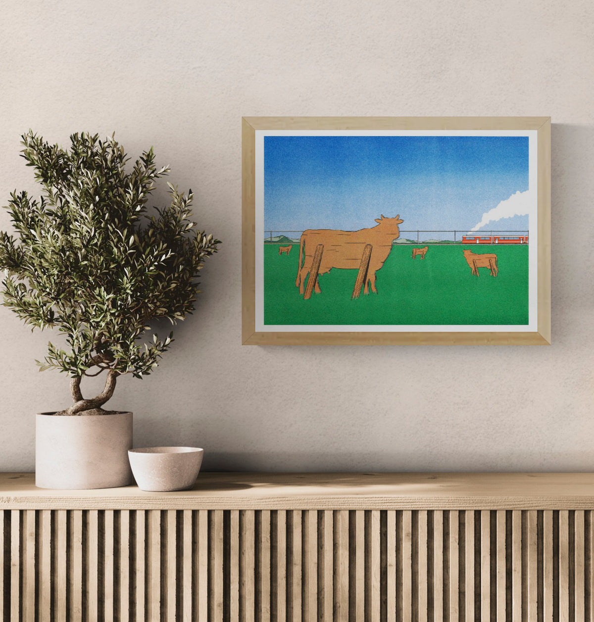 Landscape Risograph by Simon Bailly showing wooden cows in a green field watching a red train pass beneath a blue sky. Horizontal contemporary wall art with bold green, orange and blue tones.