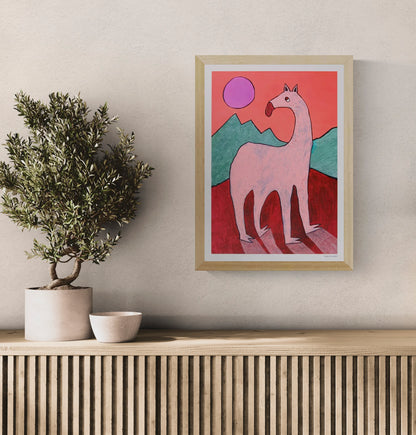 Playful and surreal illustration titled 'Beest 1' by Louise de Meester, featuring a quirky pink creature with an elongated neck set against bold red mountains, green hills, and a purple sun – a whimsical and bold art print for contemporary interiors