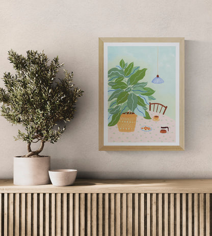 A3 illustration "Coffee Plant" by Leens showing a large leafy plant in a yellow pot, a table with a pink floral cloth, coffee cup, cookies, and carafe. Ideal for cozy kitchen or slow living decor.