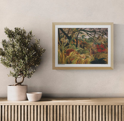 Henri Rousseau's Tiger in a Tropical Storm, a horizontal naïve-style jungle painting with a crouching orange tiger, lush green foliage, golden grasses and red tropical leaves. Digital wall art print for home decor.
