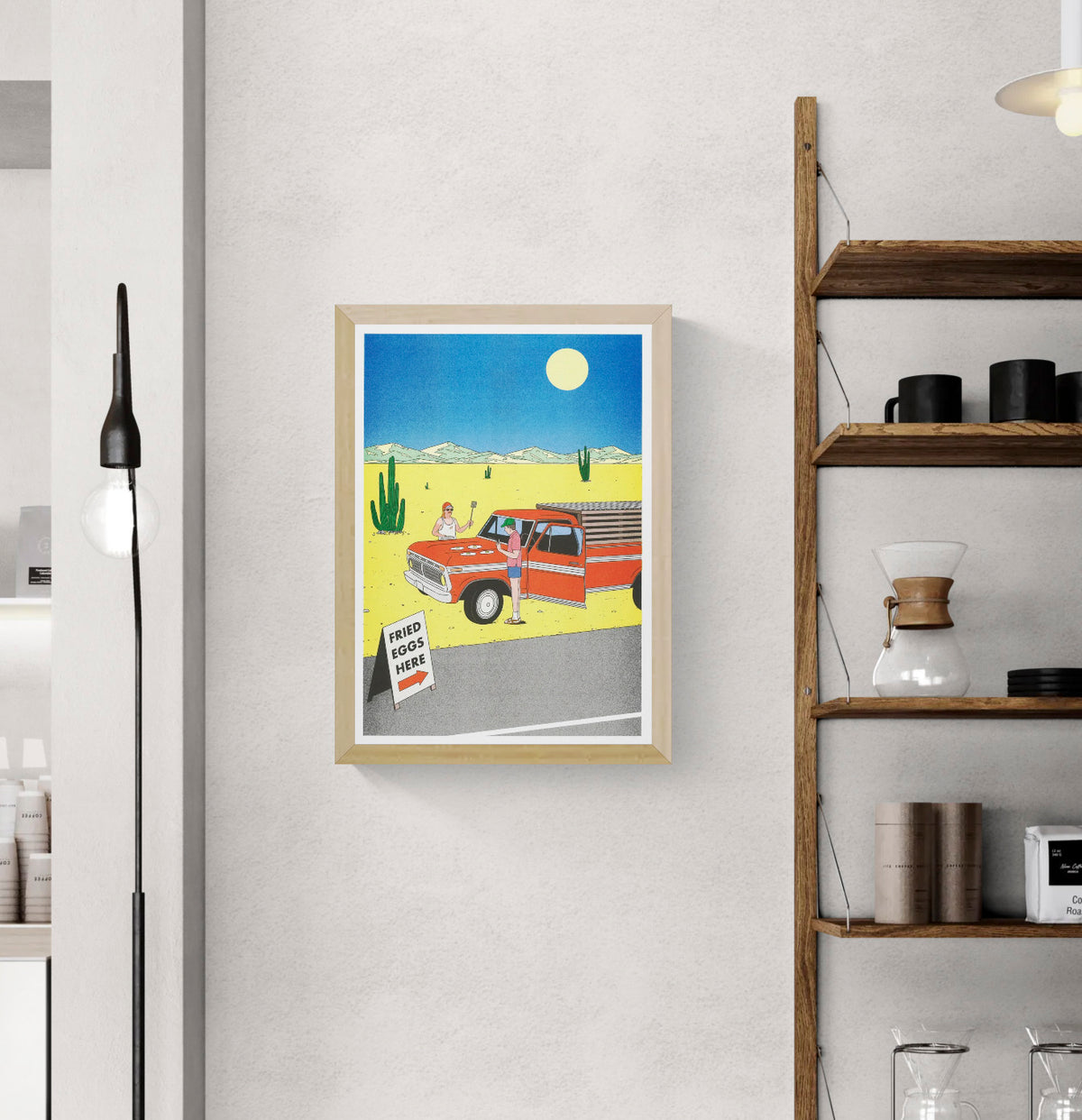 Colourful vertical risograph print by Simon Bailly showing two men cooking fried eggs on a red pickup truck in a yellow desert with cacti, mountains and a blue sky, ideal as playful kitchen or living room wall art.