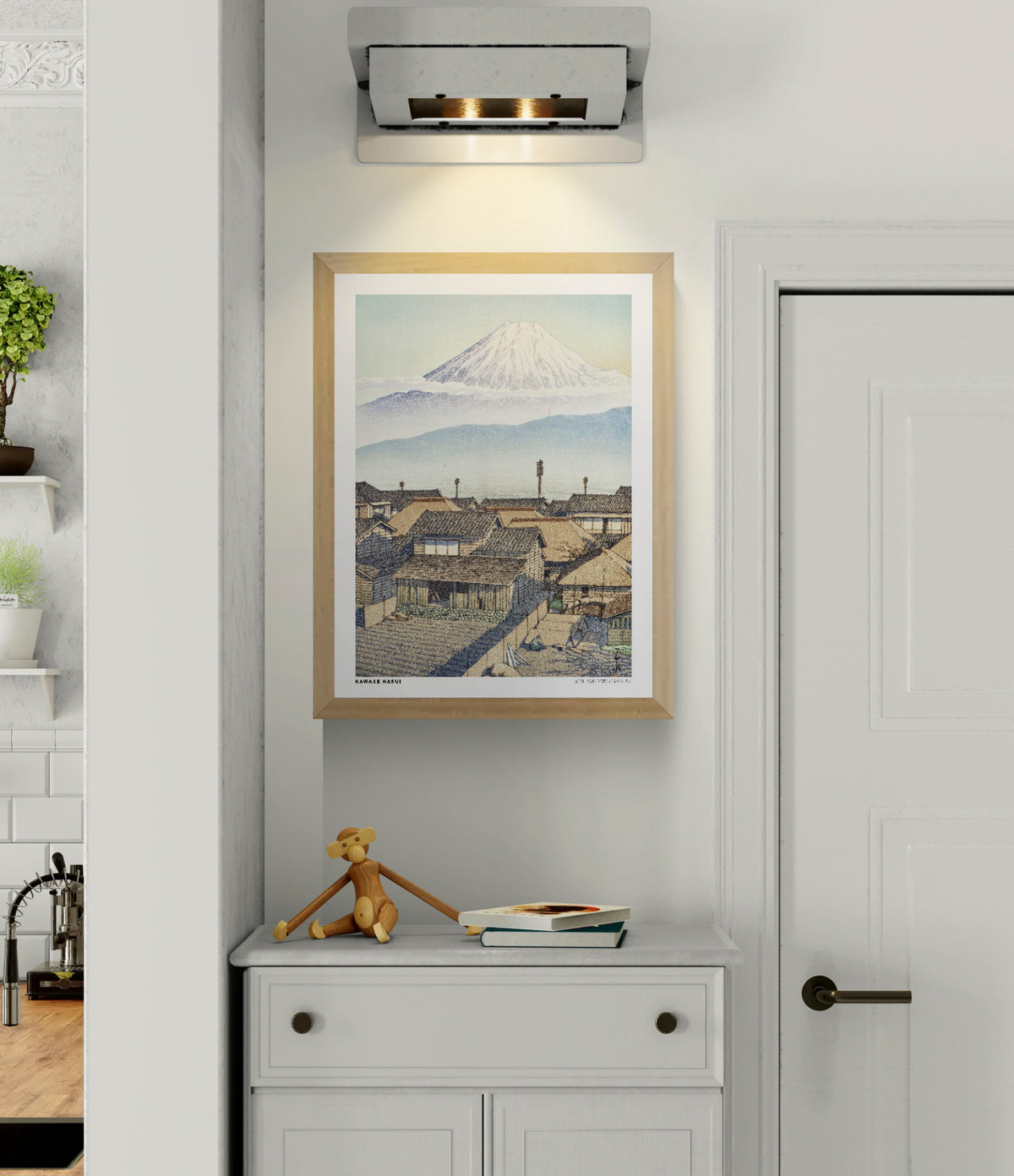 Morning in Motoyoshiwara by Kawase Hasui, Japanese woodblock-style landscape featuring snow-covered Mount Fuji above traditional village rooftops in soft blue and beige tones. Vertical digital art print for serene wall decor.