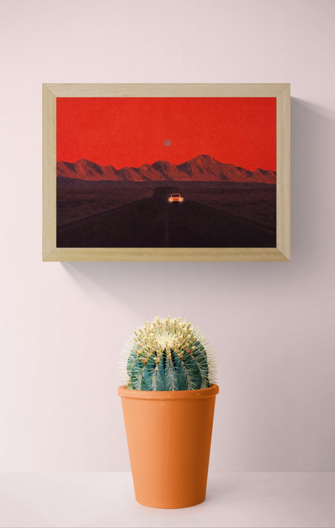 Namibia by Linde Raats, horizontal A6 giclée print showing a car driving toward dark mountains beneath a textured red sky, atmospheric wall art for modern home decor.
