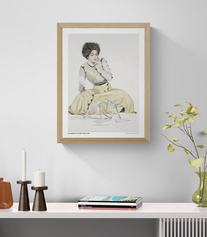 Vintage illustration by Clarence Coles Phillips showing a seated woman in a pale yellow dress holding a letter beside a collapsed house of cards. Soft pastel colors, Edwardian style, vertical digital wall art print.