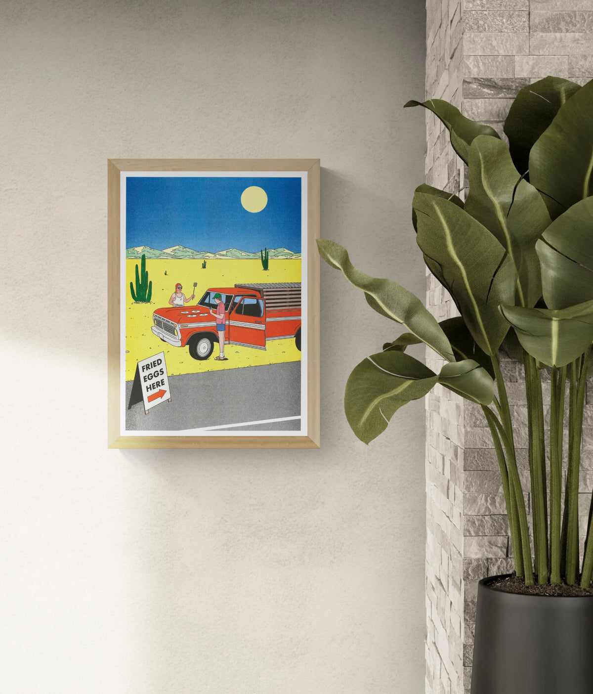 Colourful vertical risograph print by Simon Bailly showing two men cooking fried eggs on a red pickup truck in a yellow desert with cacti, mountains and a blue sky, ideal as playful kitchen or living room wall art.