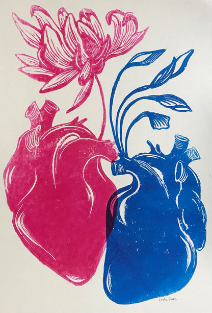 Handmade linocut print ‘Rebirth’ by Belgian artist Leda Vaes featuring a pink anatomical heart blooming into a flower and a blue heart growing flowing leaves, symbolizing renewal, connection, and new beginnings; high-contrast artistic print on textured paper.