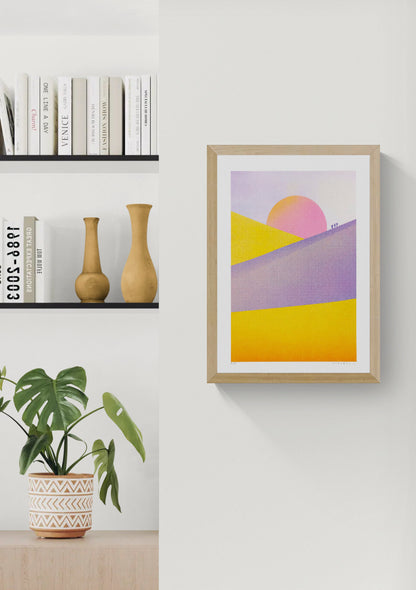 Dune Landscape - Sunset by PTRVRKD, vertical risograph print with yellow and purple desert dunes, a large pink sunset and tiny walking figures, colourful contemporary wall art for modern interiors.