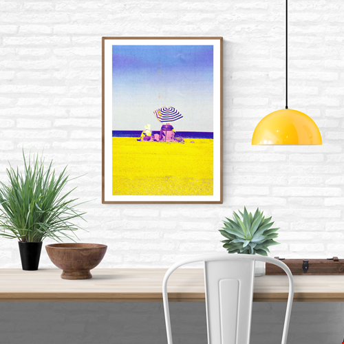 Colorful risograph art print titled “Basque Beach” by PTRVRKD, featuring two people sitting under a striped umbrella on a bright yellow beach with a soft blue-purple sky; A3 limited edition printed on Munken Pure Rough paper. Vibrant modern beach artwork ideal for coastal decor and contemporary wall art collectors.