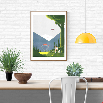 Risograph print Game Boy by Tom Haugomat — a boy playing his Game Boy in a sunny mountain valley while paragliders float in the sky, surrounded by pine trees and soft light. Minimalist French illustration blending nature, nostalgia, and modern design.