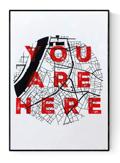 “You Are Here” A3 silkscreen print by De Zeverij featuring the city map of Antwerp with bold red typography over a black grid, handprinted with layered ink. Urban wall art for contemporary interiors.